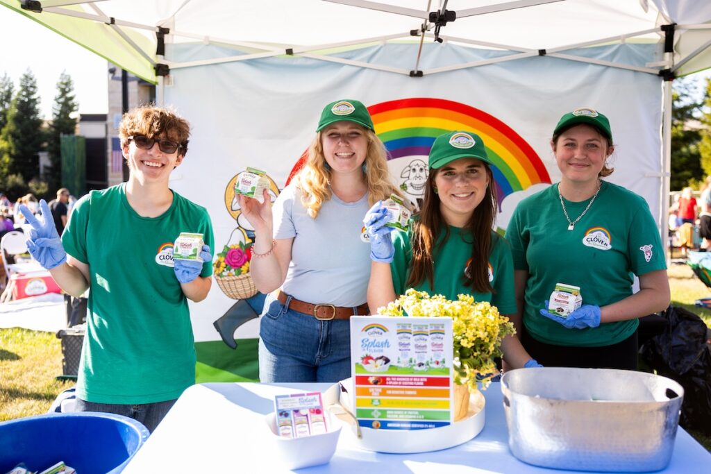 Workers from Clover Sonoma holding up milk at their tent booth